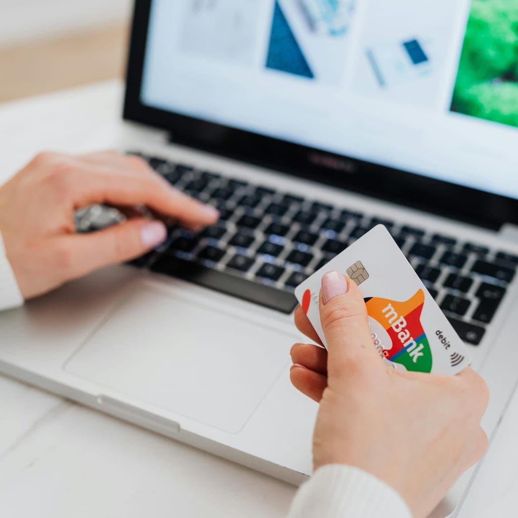 Hands holding a credit card while using a laptop